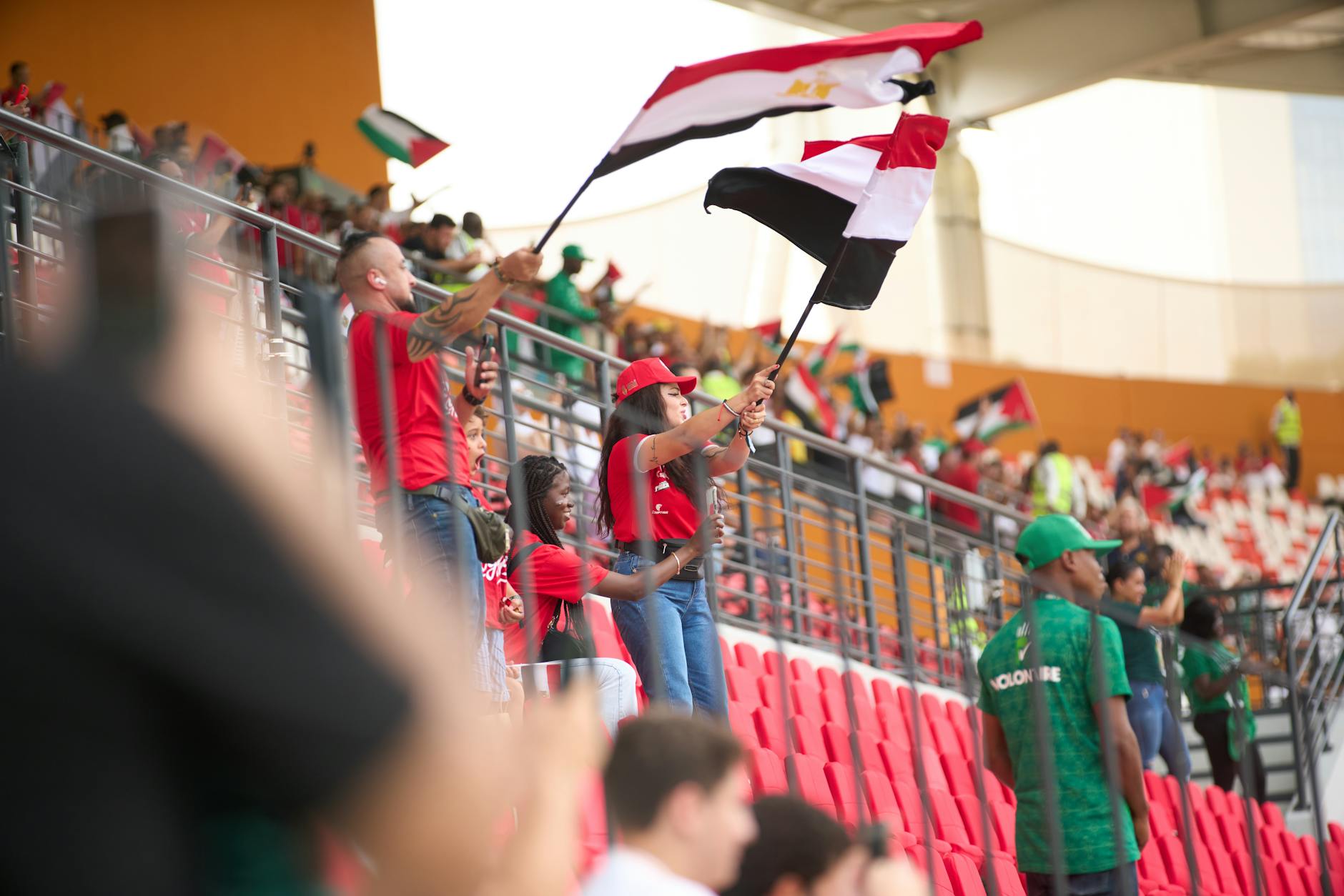 Soccer fans in the stadium wave Egyptian flags, showing their support during a lively sports match.